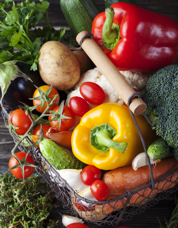 Basket with assortment of fresh vegetables on a wooden rustic background Copy space.の写真素材