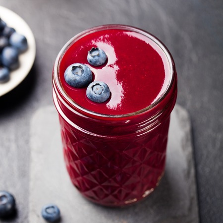 Berry smoothie with fresh blueberries on a black stone background.の写真素材