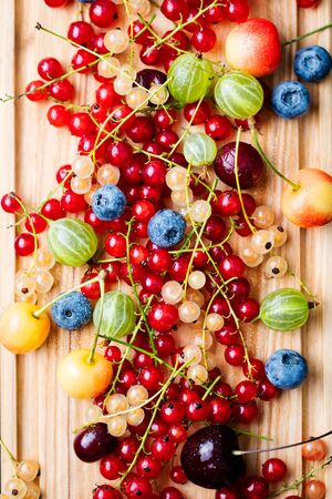 Assortment of fresh berries on wooden cutting board. Top view. Copy space.の写真素材