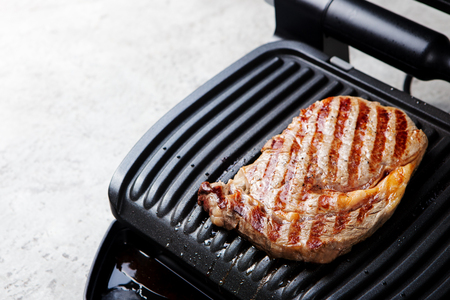 Beef steak on grill surface. Copy space. Grey stone background.の写真素材