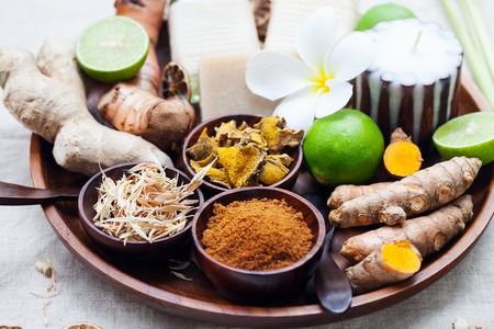 Spa, heath care set of essential oils, soap, ginger, turmeric roots and spices on a wooden tray. Grey textile backgroundの写真素材