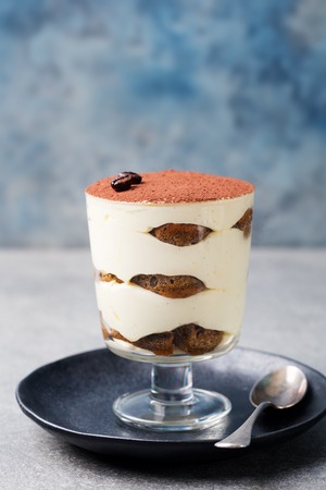 Tiramisu, traditional Italian dessert in glass on a grey stone background. Copy spaceの写真素材