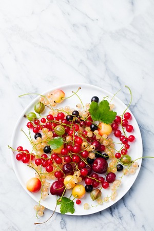 Fresh berries on a white plate. Marble background. Copy space. Top viewの写真素材