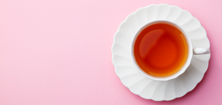 Cup of tea on pink background. Top view. Copy space.