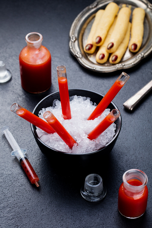 Bloody Mary cocktail in glass tubes with Witchs fingers cookies for Halloween party celebration. Slate background.の写真素材