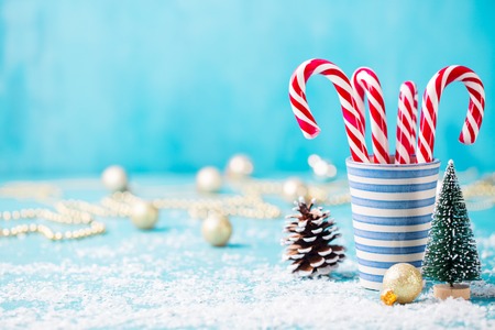 Candy canes in a glass. Christmas tree decoration with snow on blue background. Copy space.の写真素材