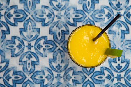 Fresh tropical fruit smoothie mango juice on blue background. Copy space. Top view.の写真素材