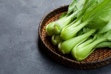 Bok choy fresh salad on wooden plate. Grey background. Copy space.の写真素材