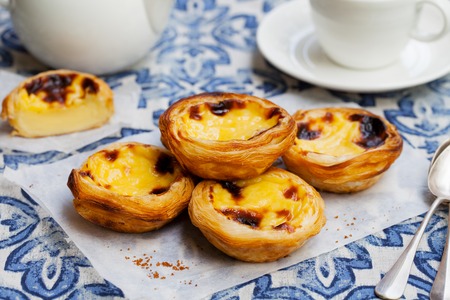 Egg tart, traditional Portuguese dessert, pastel de nata on a parchment paper. Blue background.の写真素材