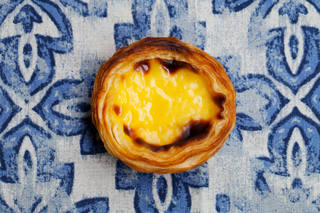 Egg tart, traditional Portuguese dessert, pastel de nata. Blue textile background. Close up. Top...