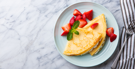 Crepes, thin pancakes with cream cheese, ricotta and fresh strawberries.の写真素材