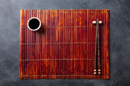 Asian table place setting with bamboo placemat, sauce bowl and chopsticks. Top view. Copy space.の写真素材