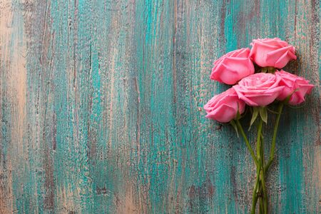 Pink roses on Colorful turquoise wooden background. Top view. Copy space.の写真素材