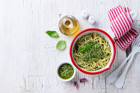Pasta spaghetti with basil pesto sauce in saucepan. White wooden background. Top view. Copy space.の写真素材