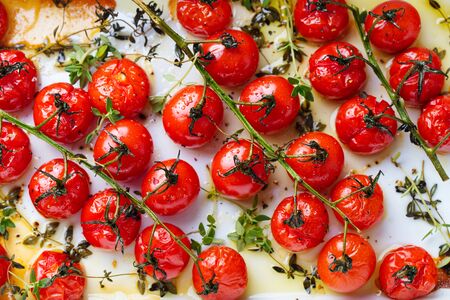 Roasted cherry tomatoes with herbs in baking dish. Top view. Food background.の写真素材