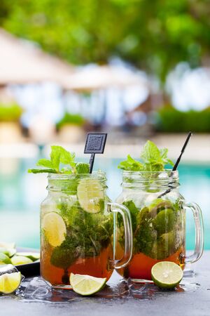 Mojito cocktail in glass jars on blue water background. Copy space.の写真素材
