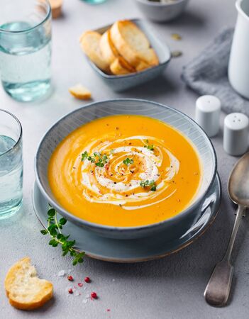 Pumpkin and carrot soup with cream on grey stone background.の写真素材