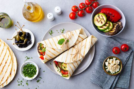 Wrap sandwich with grilled vegetables and feta cheese on a plate. Grey background. Top view.の写真素材
