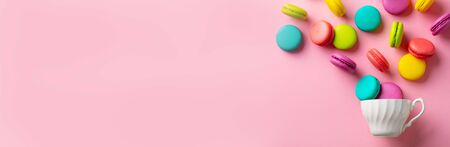 Macaroons dessert and cup of tea on pink background. Flat lay composition. Top view. Copy space.の写真素材