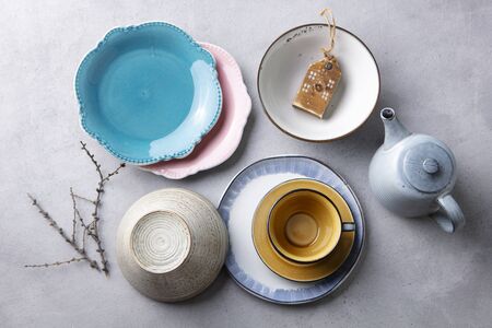 Ceramic crockery tableware, plates, bowls, cup and teapot on grey stone background. Top view.