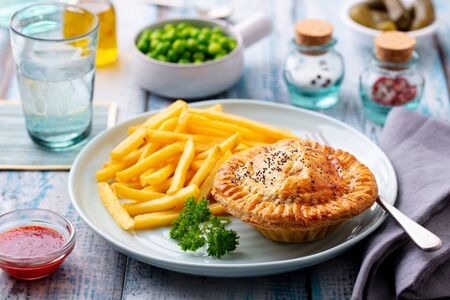 Meat pie with french fries on a white plate. Wooden background. Close up.の写真素材
