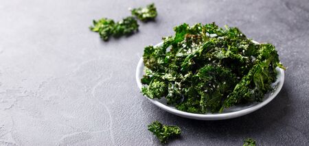 Kale chips, healthy snack on a plate. Grey background. Copy space.の写真素材