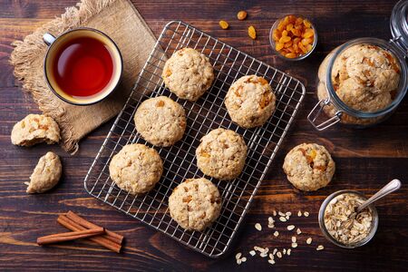 Oat vegan cookies on cooling rack with cup of tea. Wooden background. Top view.の写真素材