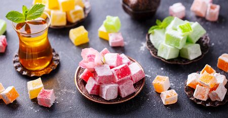 Assortment of Turkish delights with glass of tea. Grey background.の写真素材