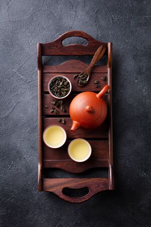 Green tea oolong in teapot and chawan bowls, cups on a wooden tray. Grey background. Top view.の写真素材