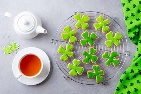 Shamrock cookies on cooling rack with cup of tea, St. Patricks Day dessert. Grey background. Top view.の写真素材