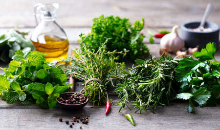 Assortment of fresh herbs, olive oil and spices. Wooden background. Close up.