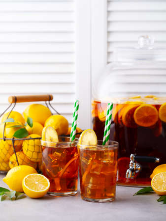 Ice tea, lemonade in glass and beverage dispenser with fresh lemons. Wooden background. Copy space.の写真素材