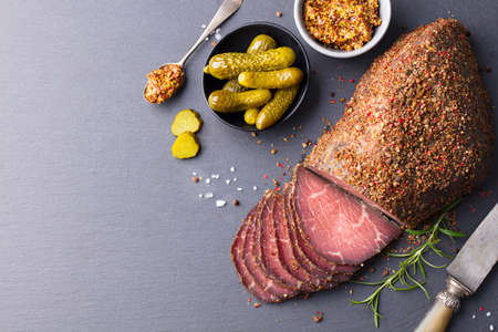 Roasted beef, pastrami on slate cutting board. Copy space. Top view.