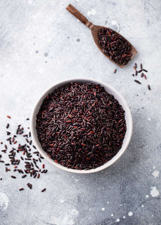 Black wild rice in a bowl. Grey stone background. Close up. Top view.の写真素材