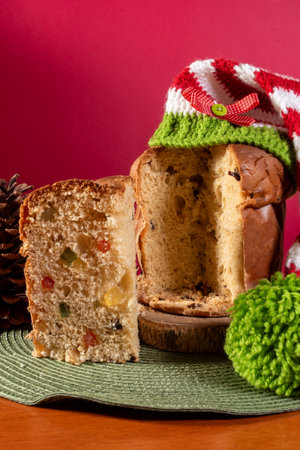 panettone, italian sweet, with santa hat on wooden table and red background.