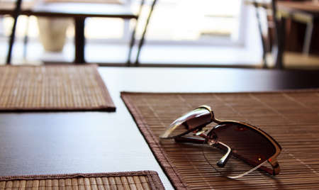 Stylish sunglasses are on the table in a cafeの写真素材