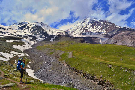 Girl with backpack hiking in the mountains. Kazbek mountain, Georgia.