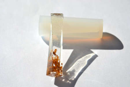 Wooden shavings in epoxy resin block. Silicone mold isolated on white background. Handmade jewelry.の写真素材