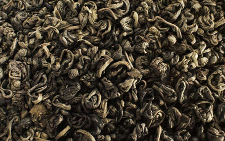 rolled dry green tea leaves. backgroundの写真素材