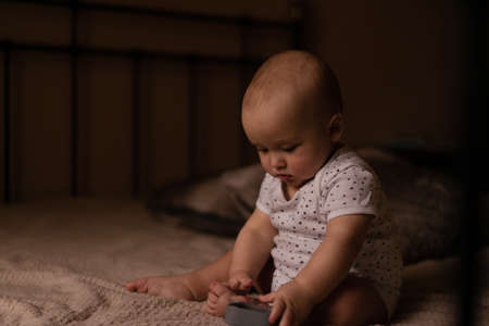 Infant boy sits in the bed and plays with toy in cozy room. High quality photo.の写真素材
