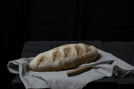 Country bread from the bakery on a linen napkin. Black boards on the background