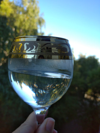 A glass of water on the background of the dawn sky, which is reflected in the glassの写真素材