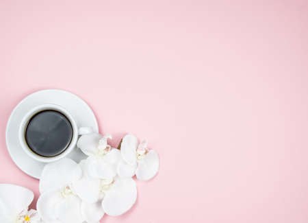 A cup of black aromatic coffee with a white orchid. Light pink backgroundの写真素材