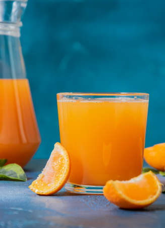 Refreshing tangerine juice in a clear glass. Tangerine slices on the table