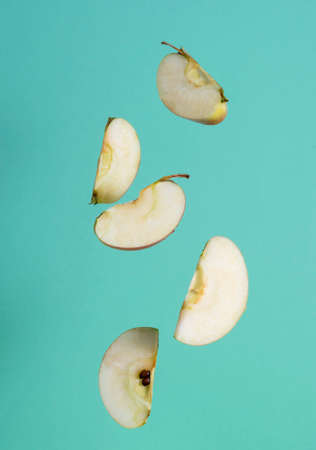 Slices of ripe apples hang in the air. Green background in the background