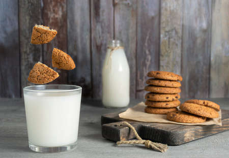 Pieces of oatmeal cookies fly into a glass of milkの写真素材