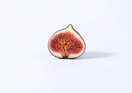 Half of a juicy ripe fig with seeds on a white background. Seeds in a close-up sectionの写真素材