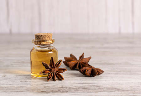 A glass jar with anise oil stands on a light wooden tableの写真素材