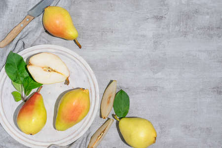 Red and yellow pears are lying on a light wooden plank. A knife on a light napkin in the background. Place for textの写真素材