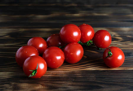 Juicy red cherry tomatoes on a green twig with beautiful highlights on the sidesの写真素材